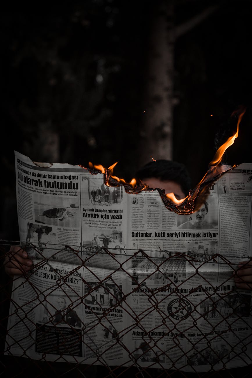 man holding burning newspaper